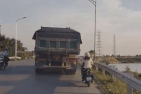 Nữ tài xế điều khiển xe máy bám đuôi xe tải khiến người xem rùng mình