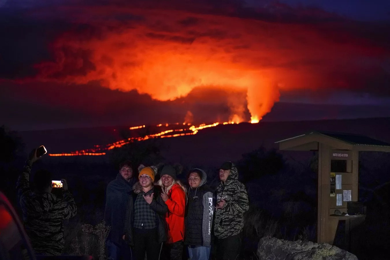 Người dân tạo dáng trước dung nham phun trào từ núi lửa Mauna Loa ở Hawaii.