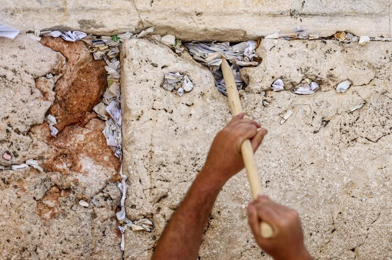 Một công nhân dọn các ghi chú được nhét trong các vết nứt của Bức tường phía Tây, địa điểm cầu nguyện linh thiêng nhất của đạo Do Thái, để lấy chỗ cho các ghi chú mới trước Năm mới của người Do Thái, tại Thành phố cổ của Jerusalem.