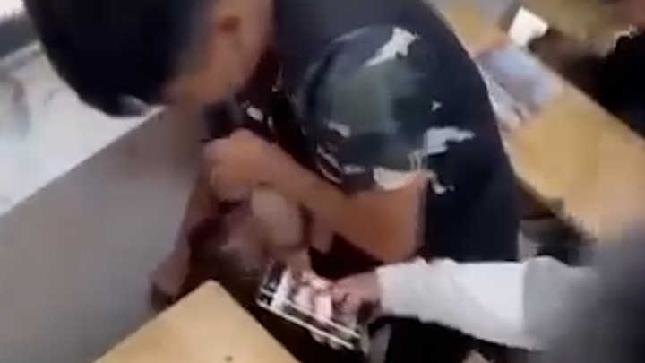 Nam sinh túm tóc dí mặt nữ sinh vào ghế. (Ảnh cắt từ clip)