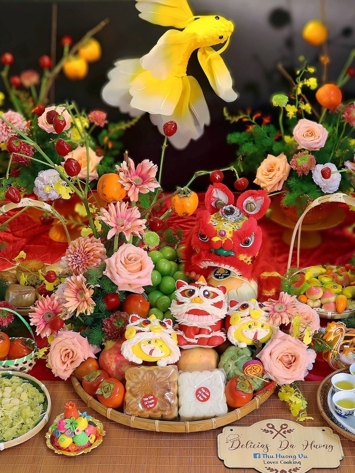 Mâm cỗ rực rỡ với hoa tươi, trái cây ngọt lành, bánh nướng, bánh dẻo đủ vị và những chú đầu lân nhỏ xinh, tượng trưng cho sự đoàn viên, ấm no. Bên cạnh là mâm quả ngũ sắc, đèn cá chép vàng bay bổng, tất cả hòa quyện tạo nên một không khí Trung thu sum vầy, rộn ràng. (Ảnh: Thu Huong Vu)