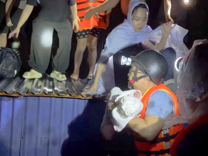 Đoàn cứu hộ kịp thời đưa bé 2 tháng tuổi trên nóc nhà về nơi an toàn. (Ảnh: NVCC)