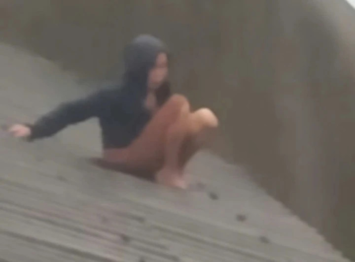 Một người phụ nữ ngồi trên mái nhà giữa mưa chờ canô ứng cứu.