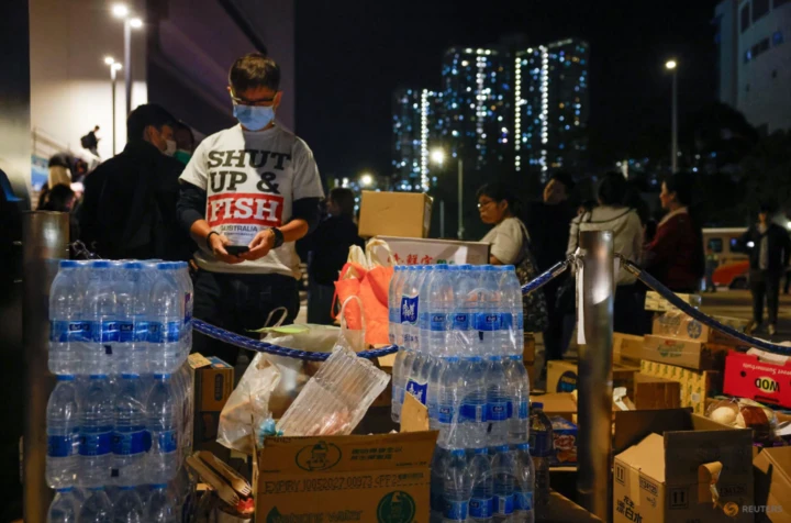 Người dân bên vật dụng cứu trợ cho người sơ tán sau vụ cháy chung cư Wang Fuk Court tại Hồng Kông, ngày 27/11. (Ảnh: Reuters)