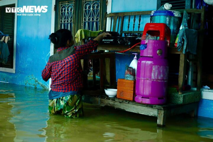 Người dân ngâm mình trong nước lũ, nấu bữa cơm cho gia đình.