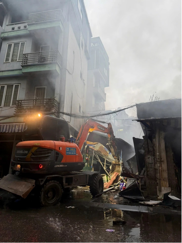 Máy xúc được huy động để phá dỡ cấu kiện sụp đổ, mở lối cho cảnh sát tiếp cận dập tắt hoả hoạn.