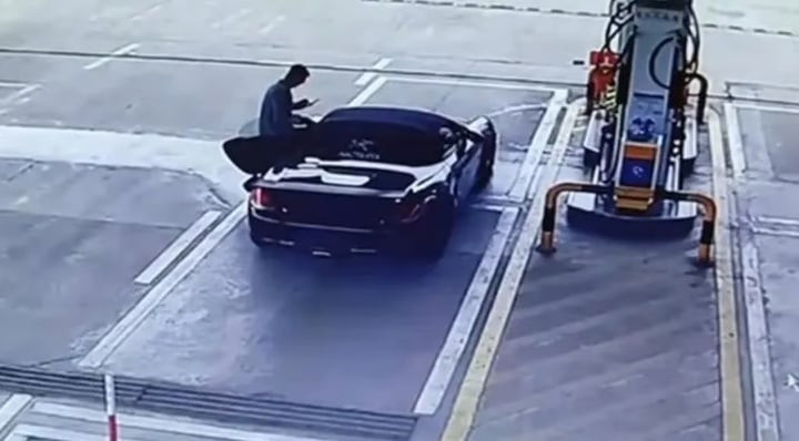 Người lái xe Porsche đứng ở cửa xe sau khi đến trạm xăng .(Ảnh: QQ)