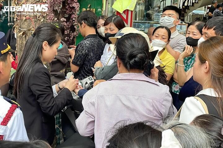 Nhân viên cửa hàng vàng phát phiếu cho khách xếp hàng chờ giao dịch vàng.