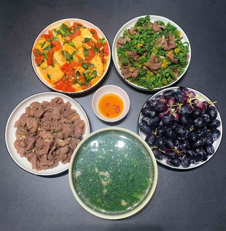 Mâm cơm có bê xào tỏi, bò xào nụ mướp, đậu sốt cà chua, canh và tráng miệng bằng quả nho.