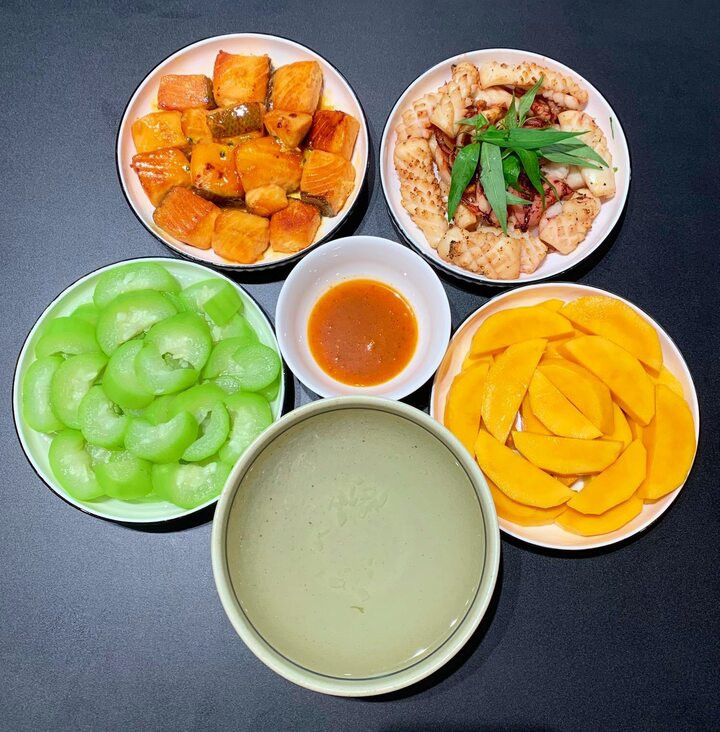 Mâm cơm hấp dẫn với cá hồi sốt chanh leo, mực nướng, mướp luộc và tráng miệng bằng xoài.