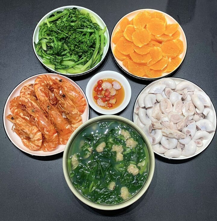 Mâm cơm này có tôm chiên, tràng luộc, canh ngao, rau cải luộc và tráng miệng bằng cam. Bí quyết luộc tràng trắng của chị Thảo Nguyên: Sau khi luộc chín thì cho vào âu nước đá lạnh rửa sạch, vớt ra đậy kín tới khi ăn.