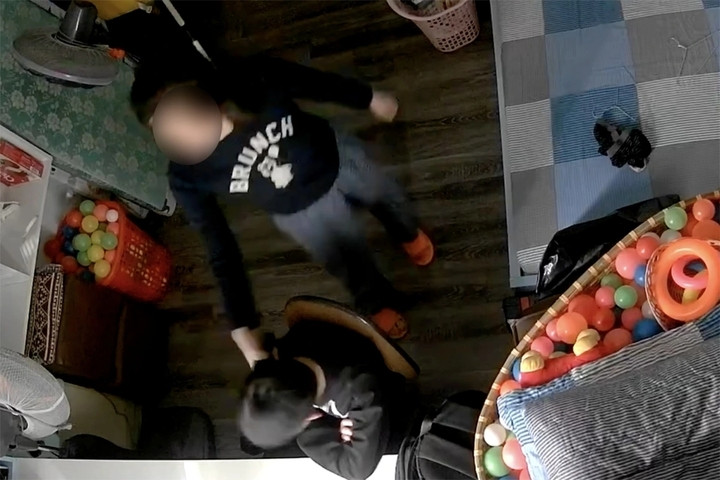 Clip ghi lại cảnh một phụ nữ cầm điện thoại đánh vào đầu bé trai, bắt bé đứng. (Ảnh chụp màn hình)