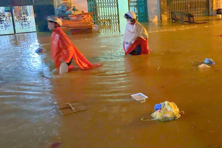 Đường ngập nặng sau mưa lớn, người dân dò dẫm qua dòng nước.