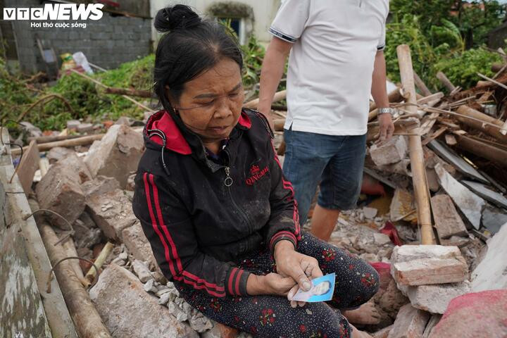 Giữa đống đổ nát, chị Sinh nghẹn ngào tìm lại tấm ảnh của người mẹ vừa khuất.