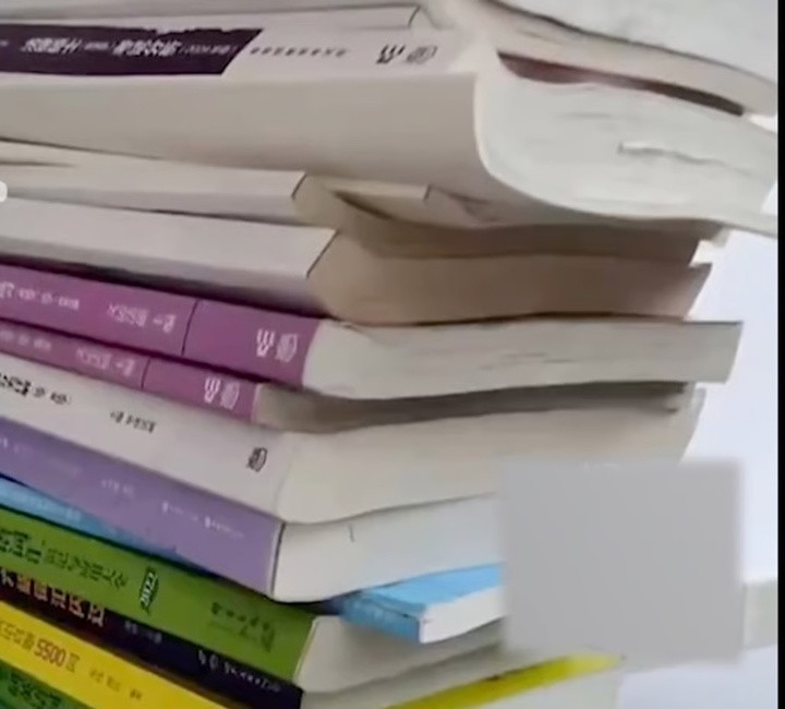 Yang nghiên cứu đống sách mà con trai để lại để vượt qua kỳ thi thạc sỹ. (Ảnh: Thepaper)