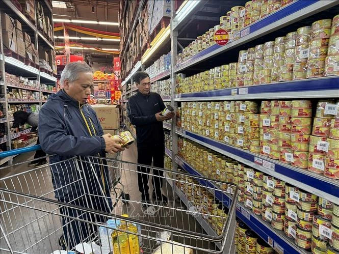 Người dân kiểm tra đồ hộp kỹ trước khi mua. (Ảnh: Tiến Vĩnh/TTXVN)