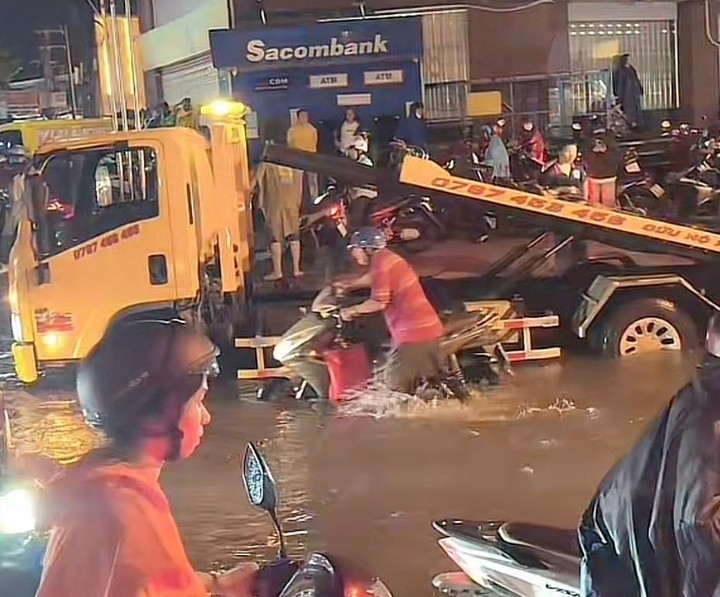 Đến tối 30/9, nhiều người đi xe máy vẫn bì bõm trên đường. Xe cứu hộ cũng tranh thủ đến trợ giúp các ô tô bị chết máy vì nước ngập. (Ảnh: B.L)
