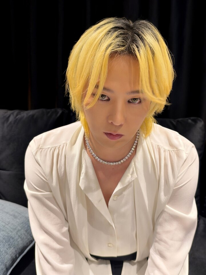 G-Dragon tạo dáng phía sau sân khấu, cho thấy hình ảnh thoải mái ngoài những màn trình diễn đầy năng lượng.