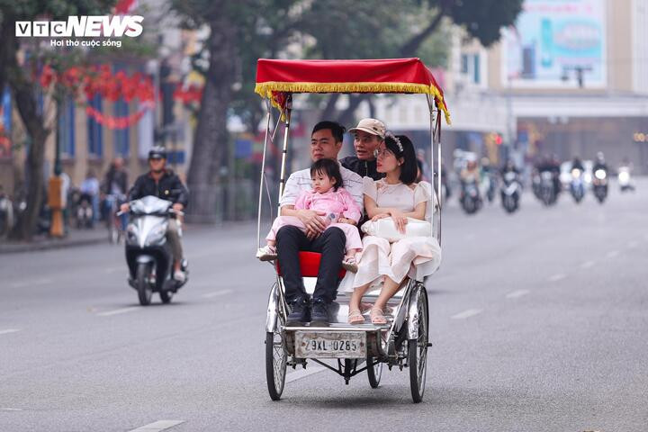 Một gia đình chọn du xuân bằng xích lô, thong thả ngắm nhìn phố phường Hà Nội trong sáng đầu năm.