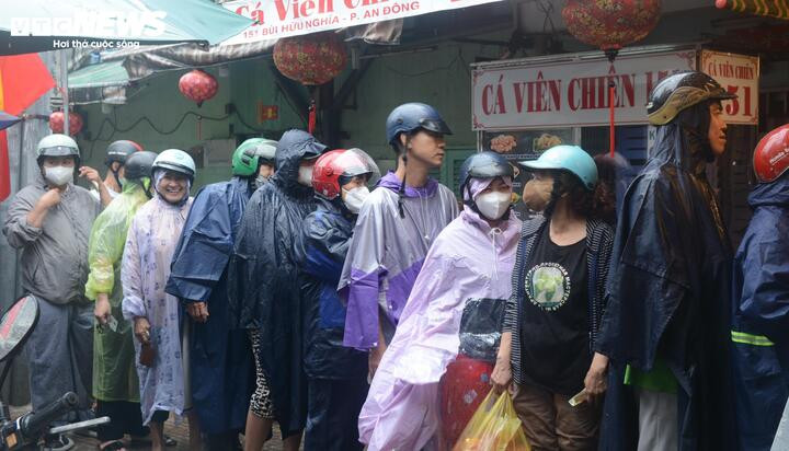 Dòng người xếp hàng dưới mưa chờ tới lượt mua hàng phía ngoài tiệm.