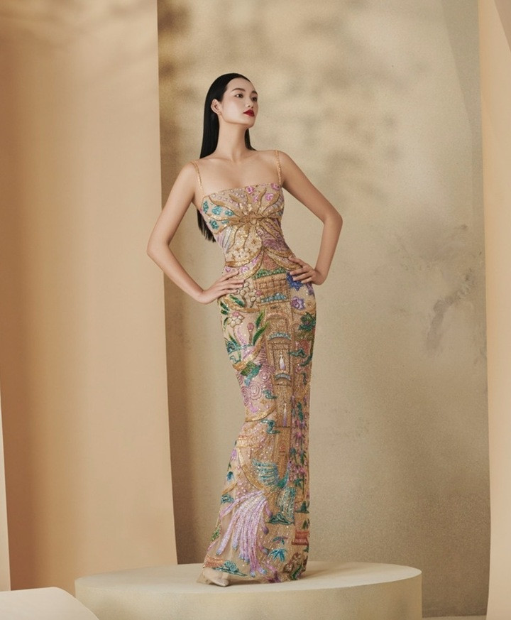 Người đẹp diện chiếc đầm dài ôm sát thêu họa tiết cố đô Huế đính kết thủ công tỉ mỉ, với hình ảnh lầu son, hoa lá, chim muông xứ Huế được thêu tay bằng chỉ màu rực rỡ trên nền lụa vàng.