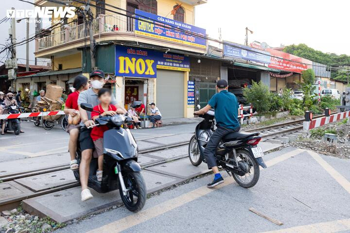 Tại khu vực ngõ 54 Ngọc Hồi, cảnh tượng tương tự diễn ra hằng ngày. Nhiều phụ huynh chở con nhỏ vẫn cố vượt rào chắn dù chỉ khoảng 60 - 90 giây sau tàu sẽ chạy qua.