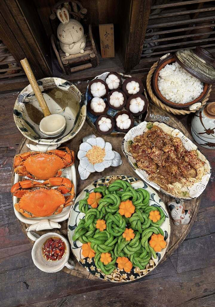 Mâm cơm có món đỗ luộc tạo hình tổ chim, thịt bò cuộn nấm kim châm nướng, cua hấp, măng cụt tráng miệng.