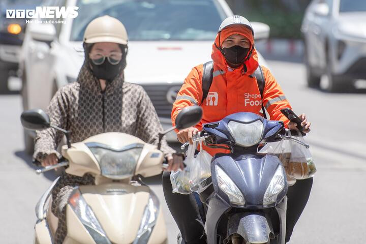 Mặt đường hấp nhiệt mạnh, hơi nóng hắt lên khiến nhiều shipper mệt mỏi, khó chịu dù đã che chắn kín. (Ảnh: Viên Minh)