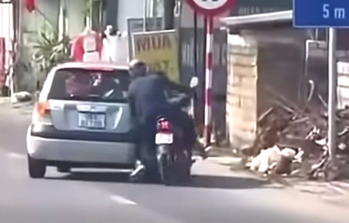 Hình ảnh ô tô lấn làn chèn ngã người đi xe máy. (Ảnh cắt từ clip)