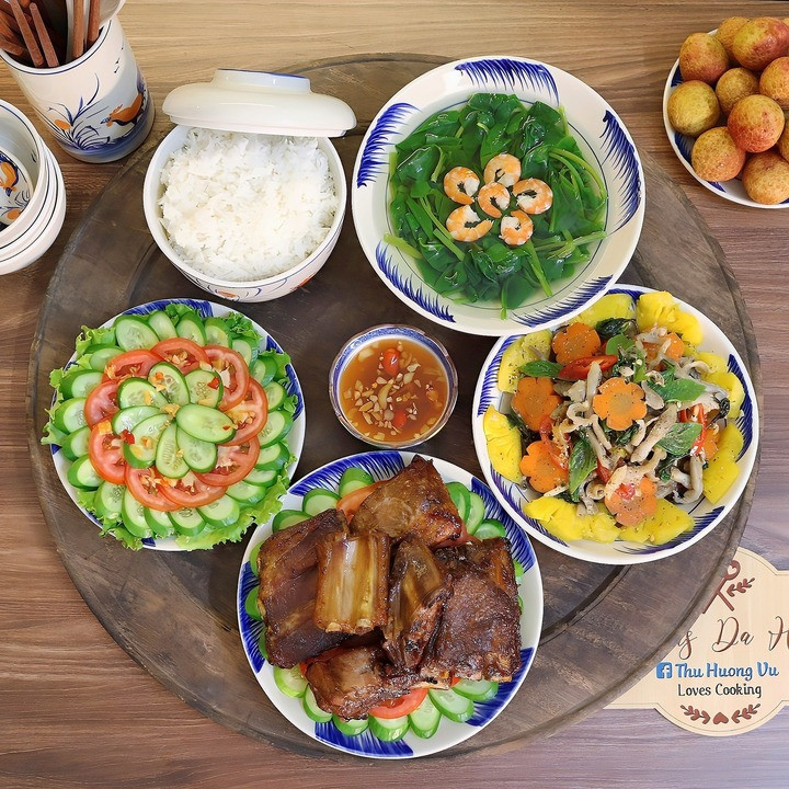 Mâm cơm có món sườn nướng ngũ vị, ốc móng tay xào, canh rau mồng tơi nấu tôm, salad cà chua trộn dưa chuột.