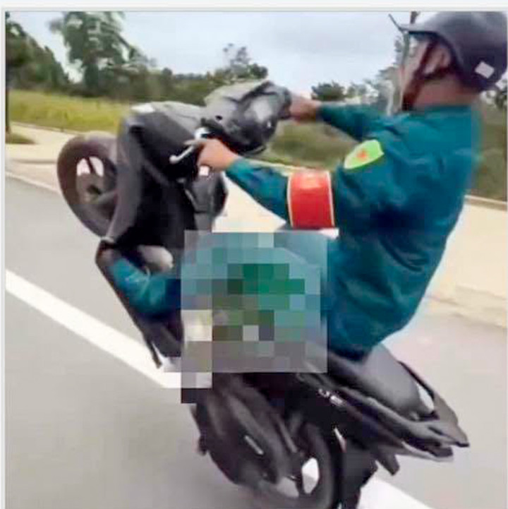 Hình ảnh T.H.A. mặc trang phục dân quân tự vệ, bốc đầu xe máy trên đường Lạc Long Quân, Lào Cai.