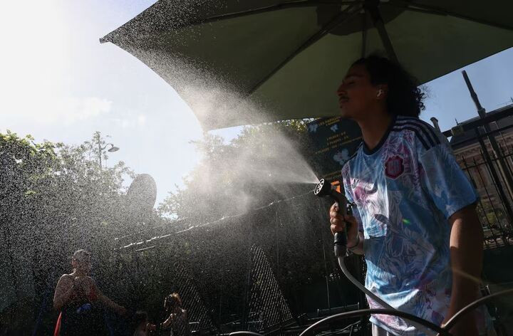 Người đàn ông phun nước hạ nhiệt trong cái nóng gay gắt tại công viên Buttes Chaumont Paris, Pháp. (Ảnh: Reuters)