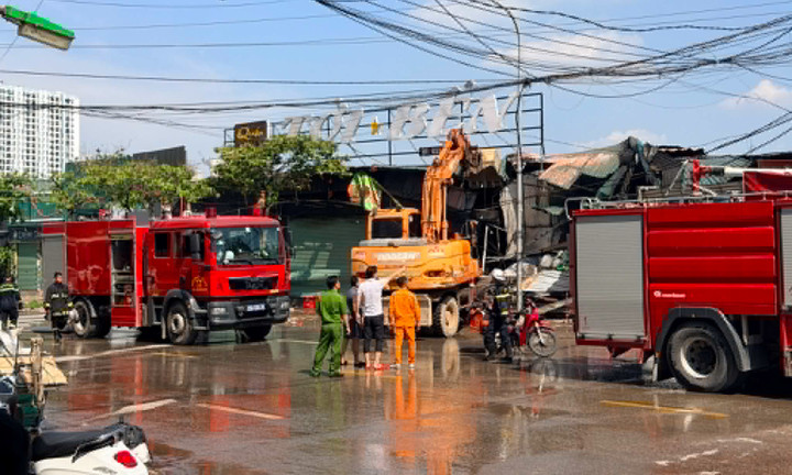 Lực lượng chức năng huy động máy xúc há dỡ phần tôn quây, phục vụ công tác xử lý. (Ảnh: Đ.H.)