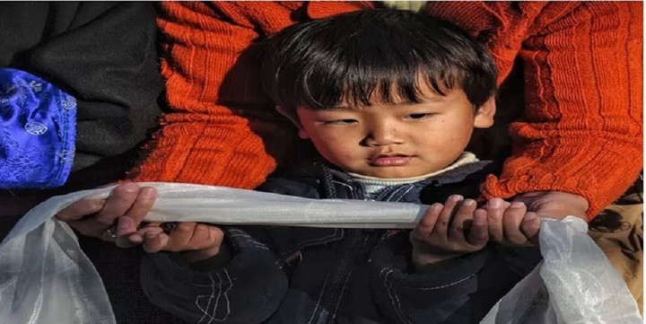 Một đứa trẻ Tây Tạng đang học nghi thức tặng khăn Khata.