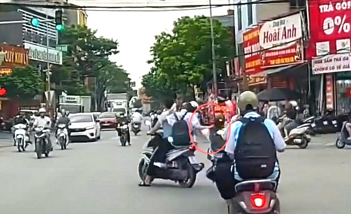 Đang đi cùng nhau trên đường, nữ sinh ngồi sau xe máy bất ngờ đưa tay túm tóc kéo nữ sinh điều khiển xe phía trước. (Ảnh cắt từ clip).